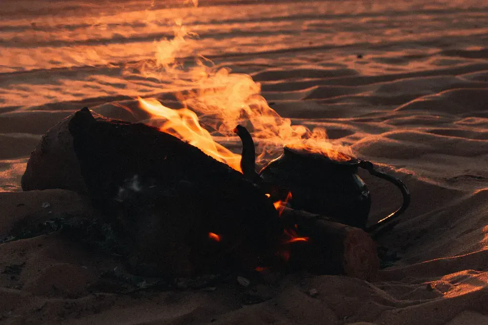 Feu de camp sur le sable au coucher du soleil